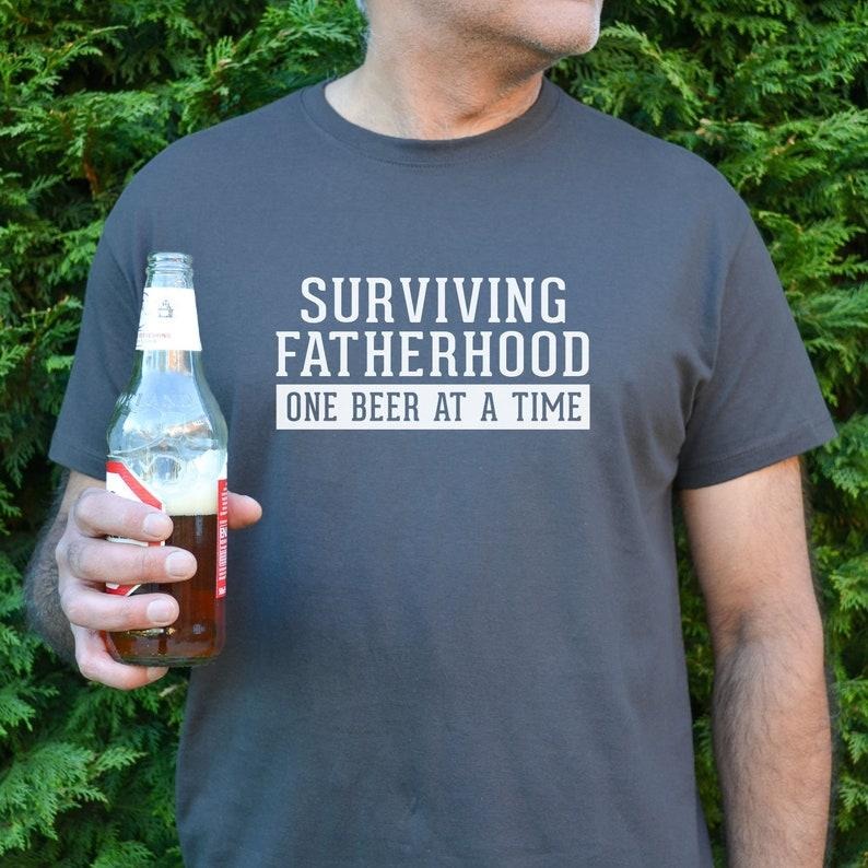 Surviving Fatherhood Dad Dad Beer T-Shirts, Hoodie, Sweatshirt - T-Shirt, Sweatshirt, Hoodie